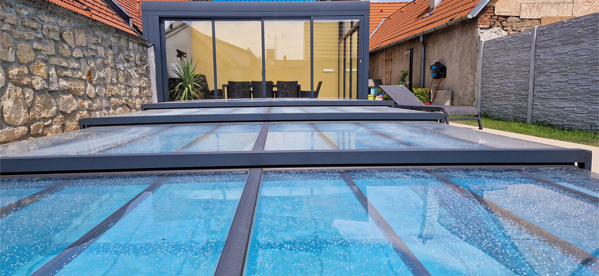 Vue détaillée de l'auvent bas en aluminium de la piscine, doté d'un cadre gris moderne, dans la cour.