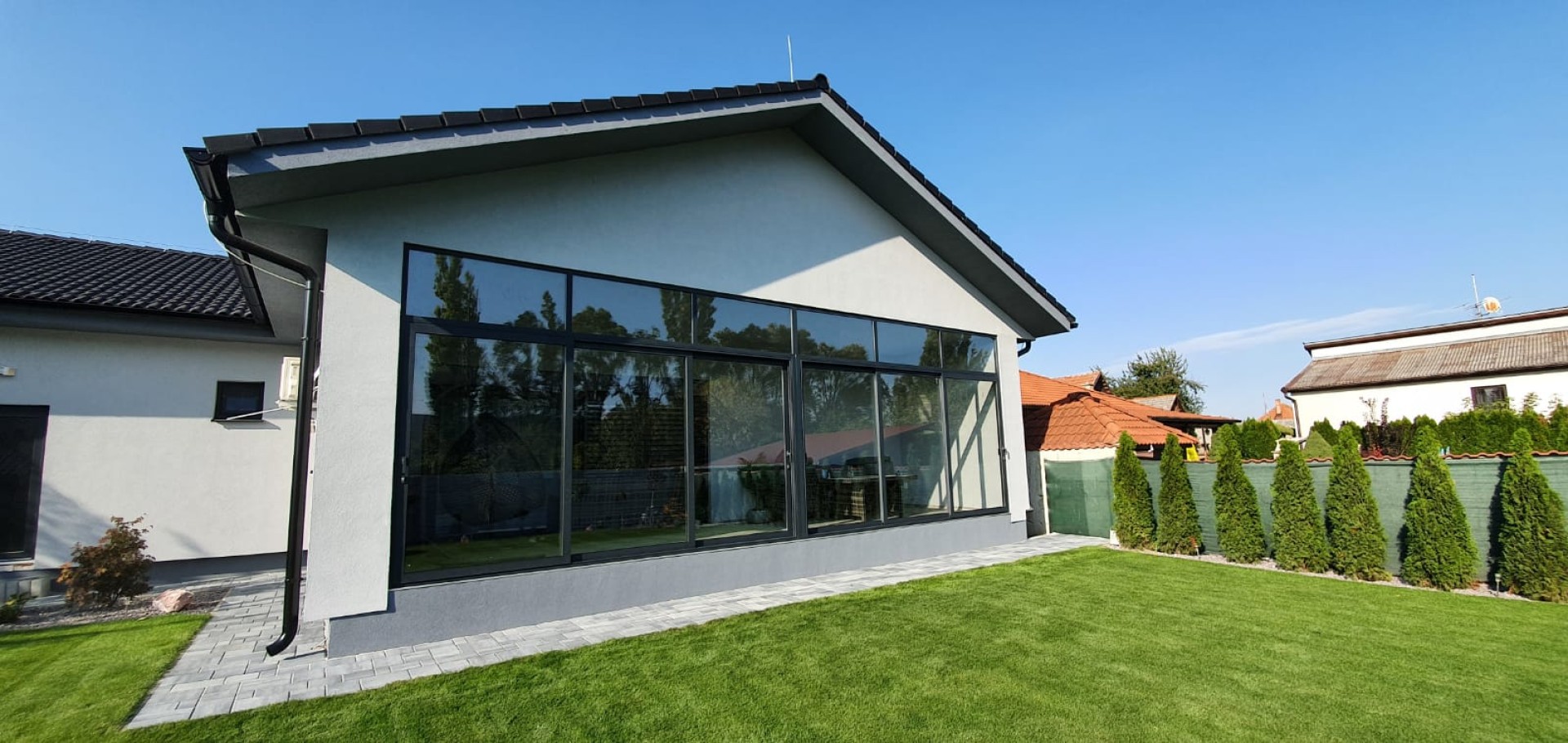 Vitrage moderne de la terrasse d'une maison individuelle, avec des profilés gris et une vue sur le jardin