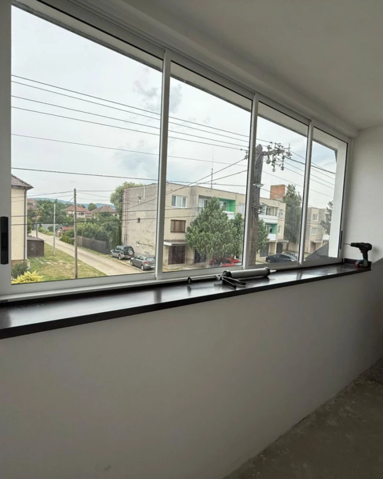 Vue depuis l'intérieur sur les baies vitrées coulissantes du balcon, récemment installées, donnant sur la rue.