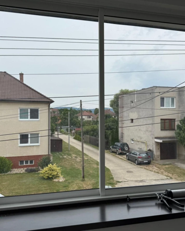 Vue à travers les nouvelles baies vitrées sur la rue bordée de maisons individuelles et de voitures à Skalica.