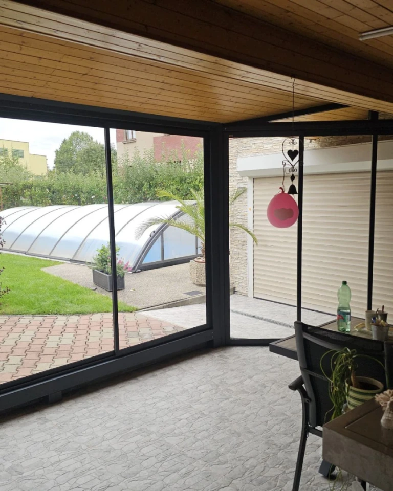 Vue depuis l'intérieur sur la terrasse vitrée donnant sur le jardin et la piscine
