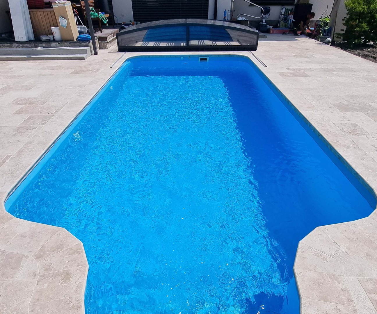 Vue sur la piscine en plein air aux eaux bleues, avec en arrière-plan une couverture de piscine sans rails.