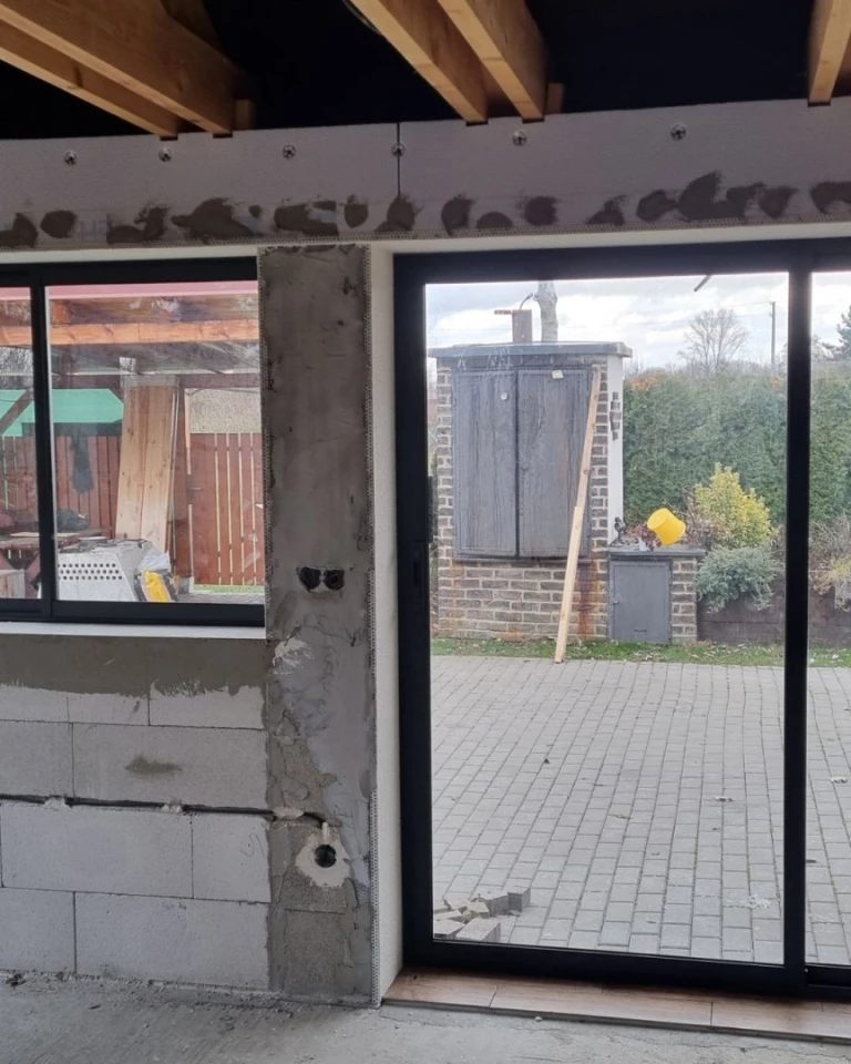 Terrasse en cours de construction, équipée d'un vitrage en aluminium « Robust » et offrant une vue sur l'extérieur