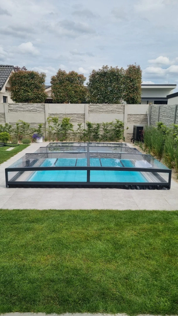 Une couverture de piscine basse et moderne, de couleur anthracite, dans le jardin d'une maison individuelle.