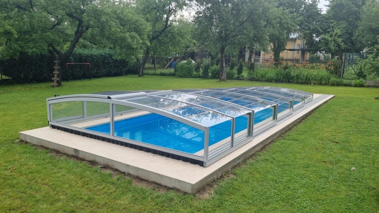 Une couverture de piscine moderne et basse, dotée de panneaux transparents, dans le jardin