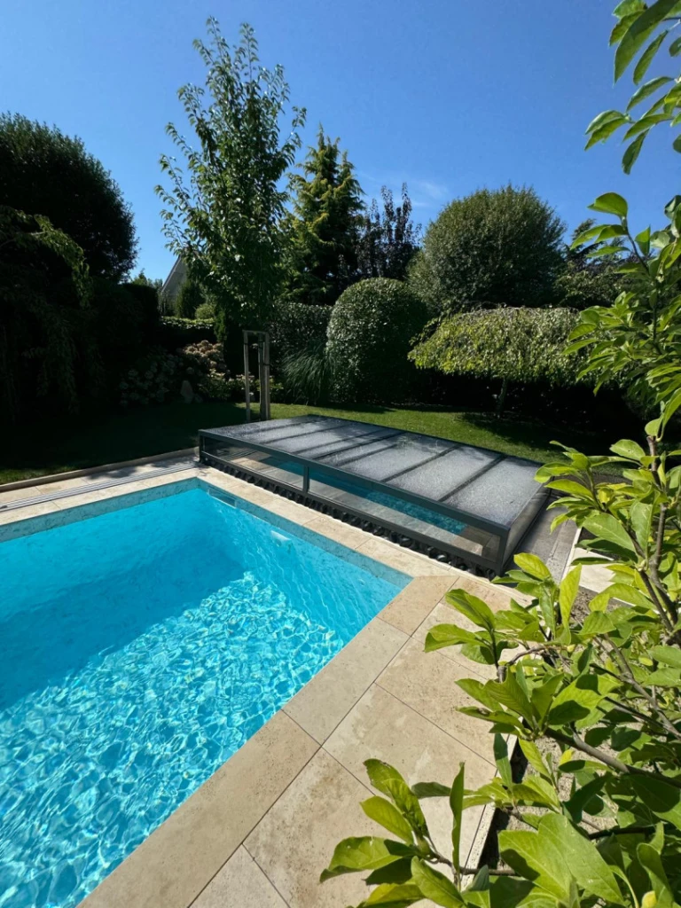 Une couverture moderne et basse pour la piscine du jardin, aux eaux d'un bleu limpide.