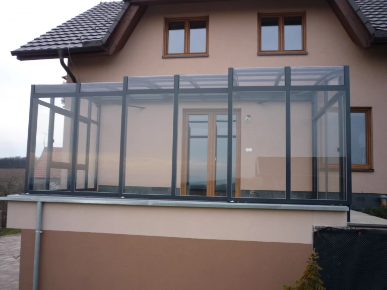 Une véranda moderne vitrée à baies coulissantes sur la terrasse d'une maison individuelle