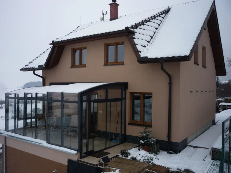 Une véranda vitrée coulissante sur la terrasse d'une maison individuelle, sous la neige