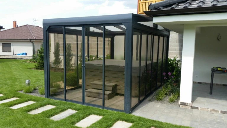 Un abri moderne vitré avec un jacuzzi, situé dans le jardin d'une maison individuelle.