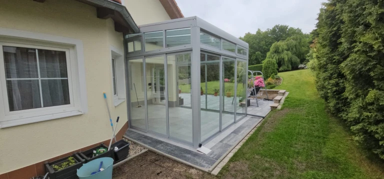 Une véranda moderne vitrée, dotée d'une structure en aluminium, attenante à une maison individuelle