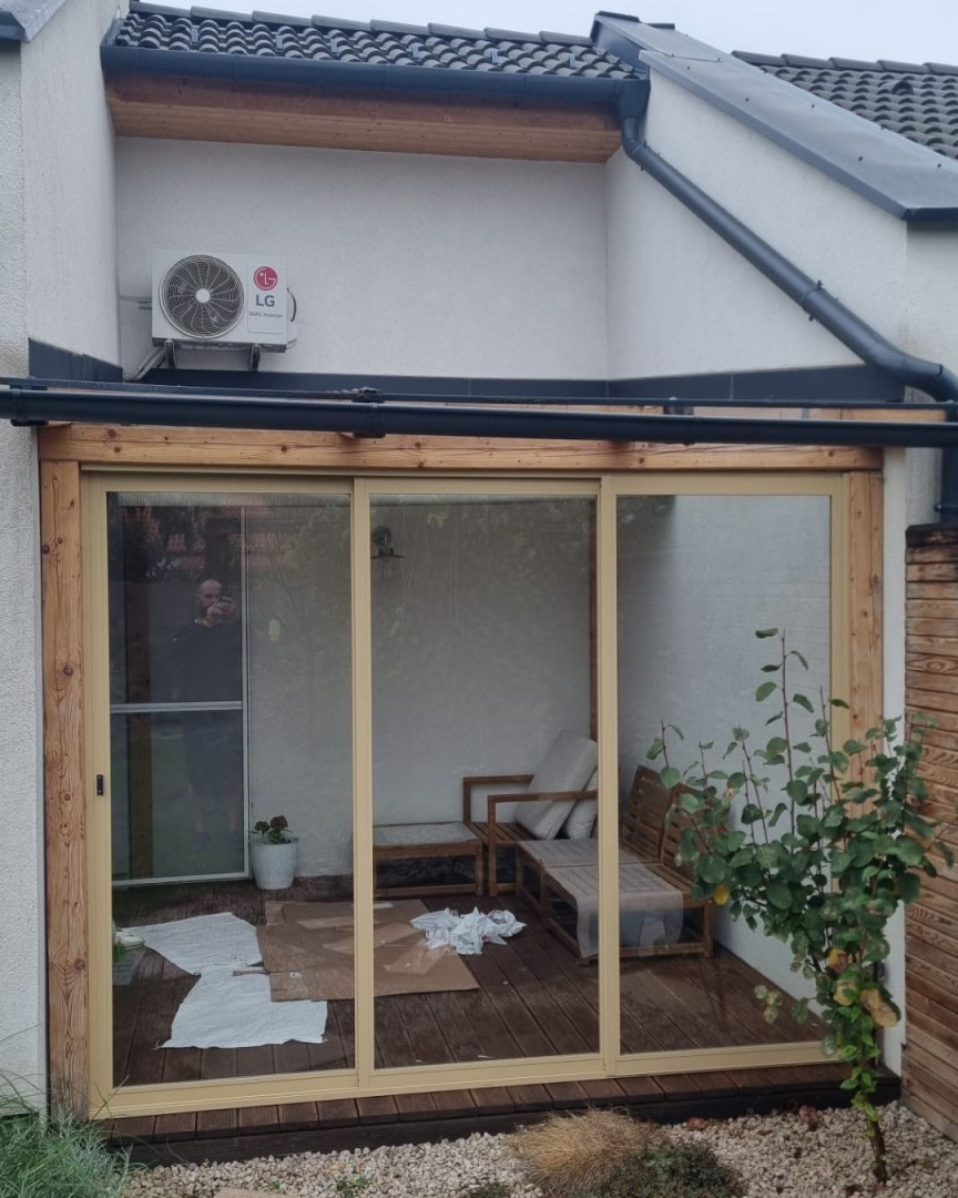 Des portes coulissantes vitrées modernes sur la terrasse, avec un cadre en bois et du mobilier d'extérieur.