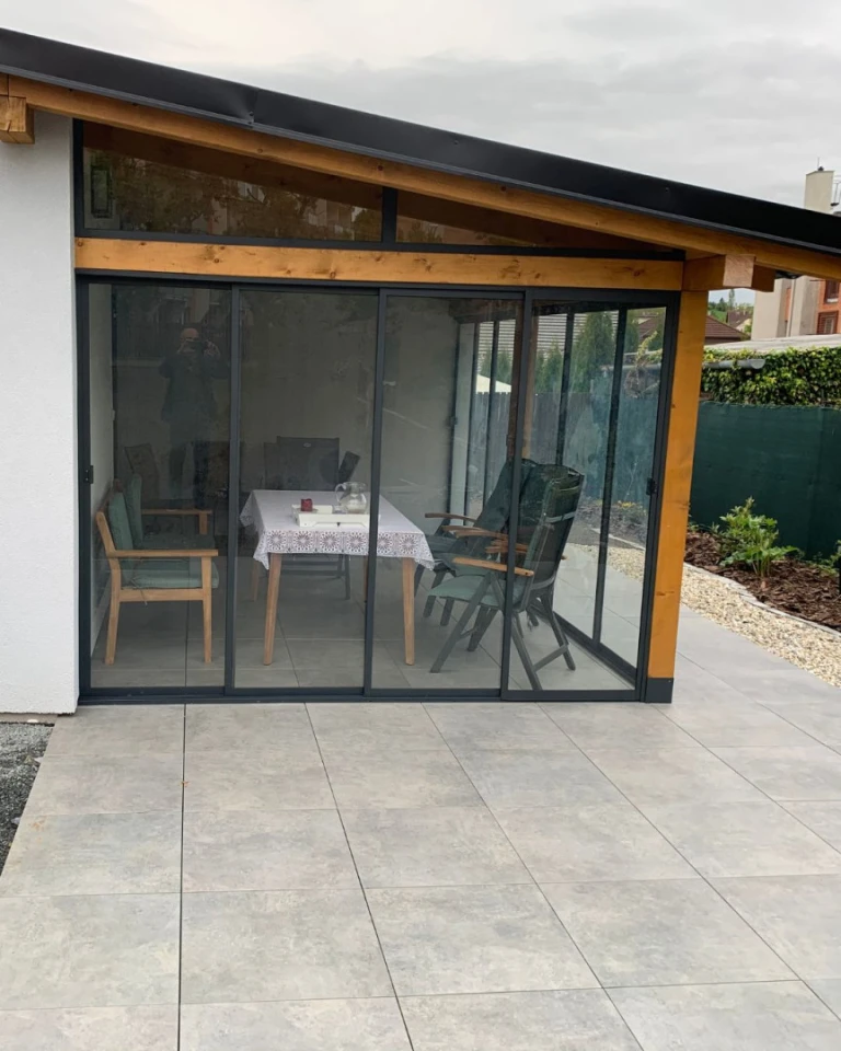 Des portes coulissantes vitrées modernes donnant sur la terrasse, avec une structure en bois et un coin salon extérieur.