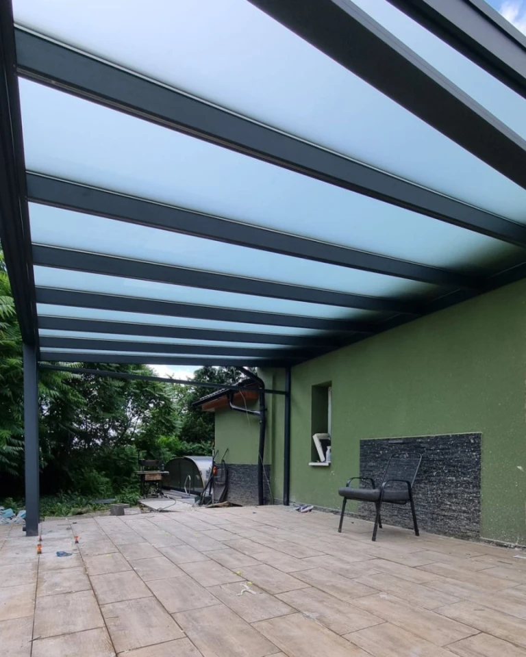 Une pergola moderne en aluminium avec un vitrage dépoli sur la terrasse d'une maison individuelle