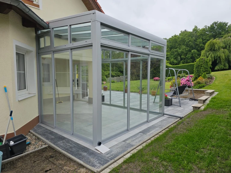 Une véranda moderne et vitrée de type « Robust », dotée d'une structure en aluminium, attenante à une maison individuelle